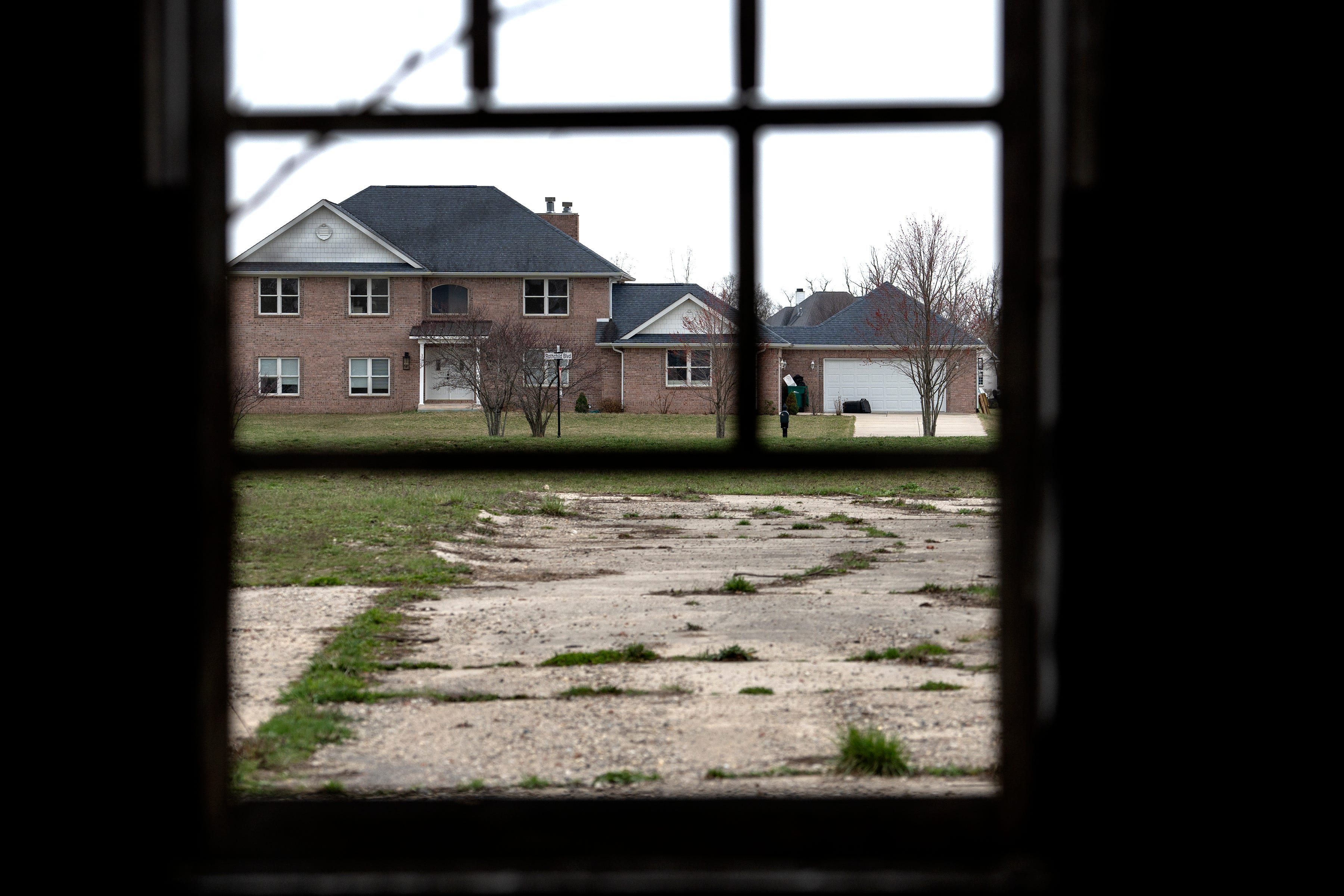 Buildings from an old farm are empty and deteriorating at 7802 Marsh Rd., Monday, March 18, 2024 in the Traders Point neighborhood. The buildings are slated for demolition to ready the property for houses to be built. A neighborhood of houses can be seen through a barn's window.