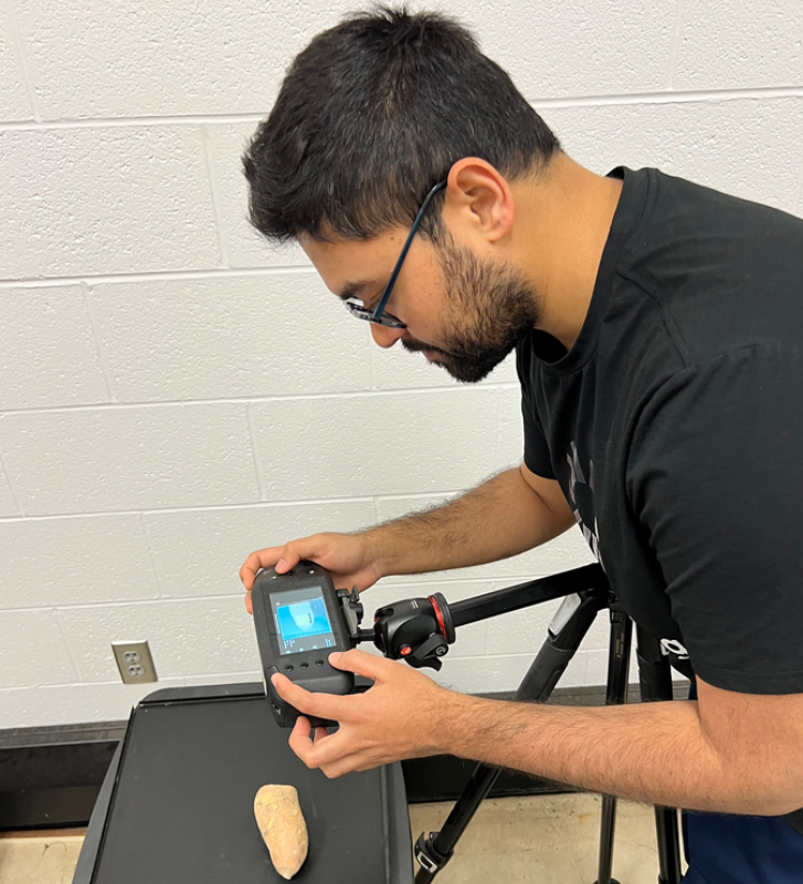 Md Toukir Ahmed, a doctoral student in agricultural and biological engineering at the University of Illinois Urbana-Champaign, takes images of a sweet potato with a hyperspectral imaging camera.